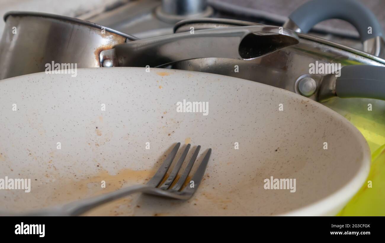 The kitchen utensils in the wash basin need to be washed. A pile of