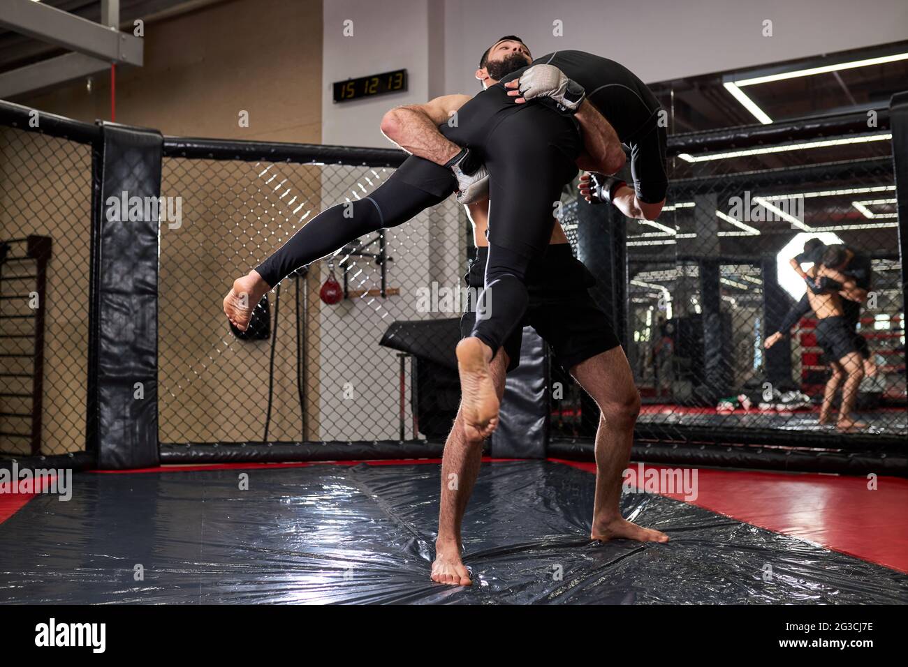 Fighters of MMA boxers are fighting without rules in cage ring at gym