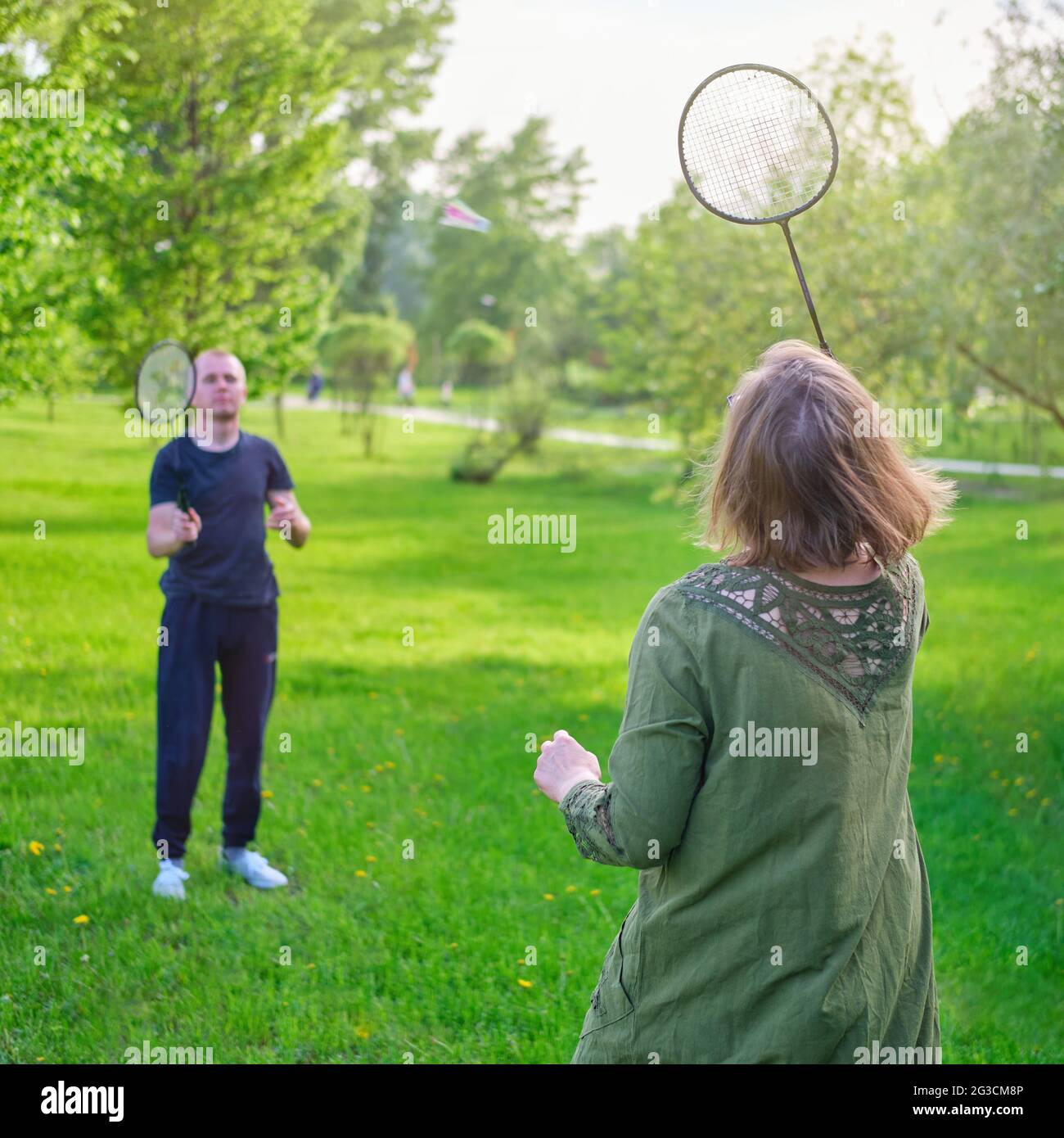 Family playing badminton in the park, mom and son with rackets and