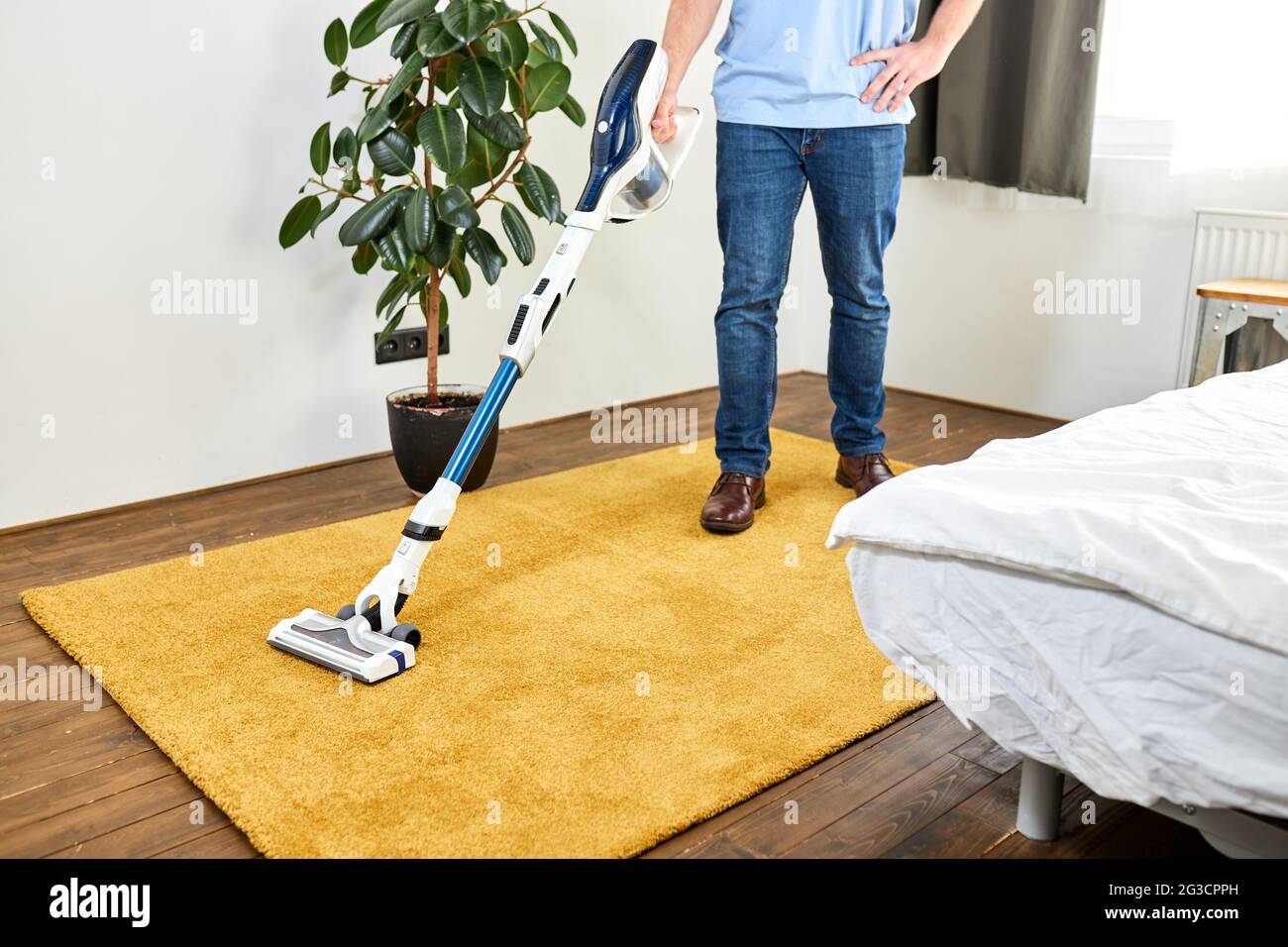 man cleaning floor with vacuum cleaner in modern white living room ...