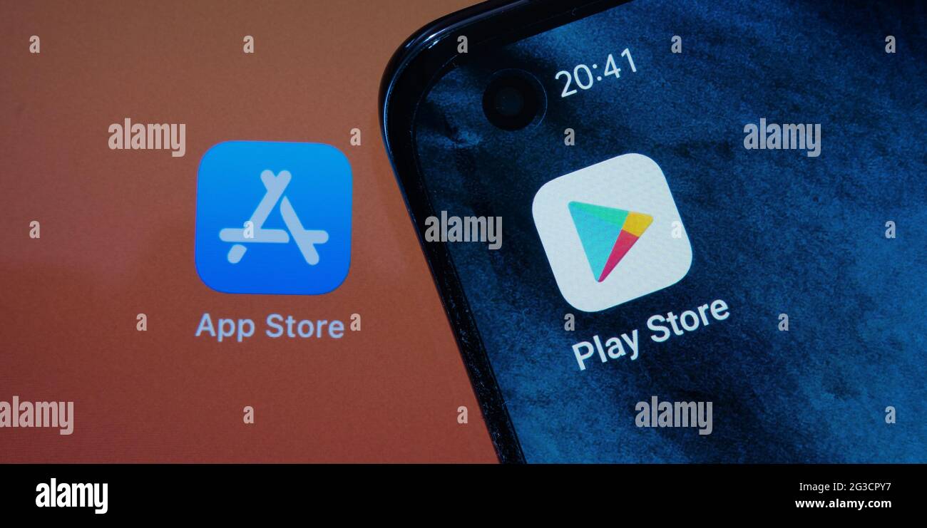 Google Play Store and blurred App Store apps seen on android smartphone and Apple macbook M1 laptop screens. Concept. Stafford, UK, June 15, 2021. Stock Photo