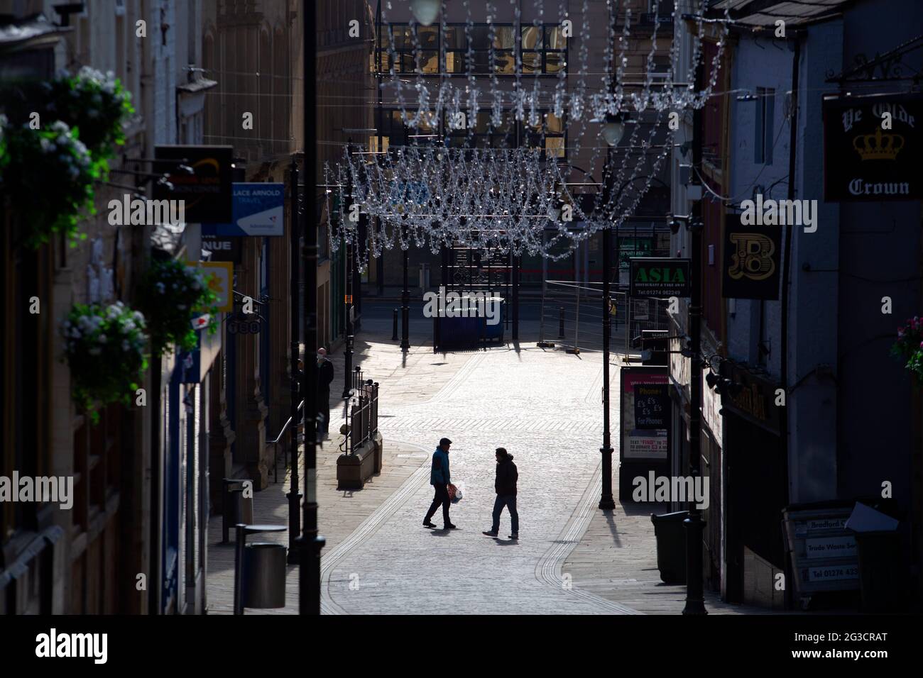 Two men cross each others paths in the unusually quiet and empty shopping streets of Bradford City Centre in west Yorkshire as the coronavirus pandemi Stock Photo