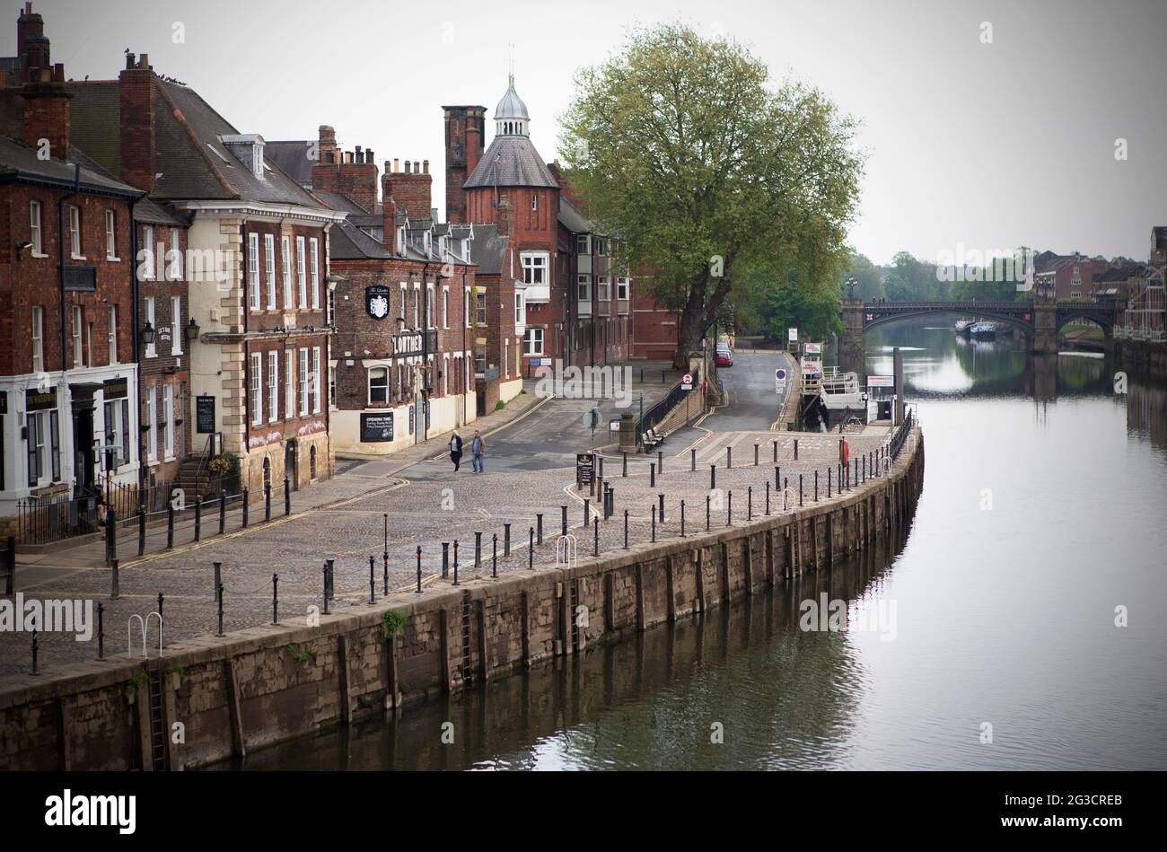 A couple walk alongside the River Ouse in York city centre, north Yorkshire. An area which is usually busy and teeming with tourists and locals drinki Stock Photo