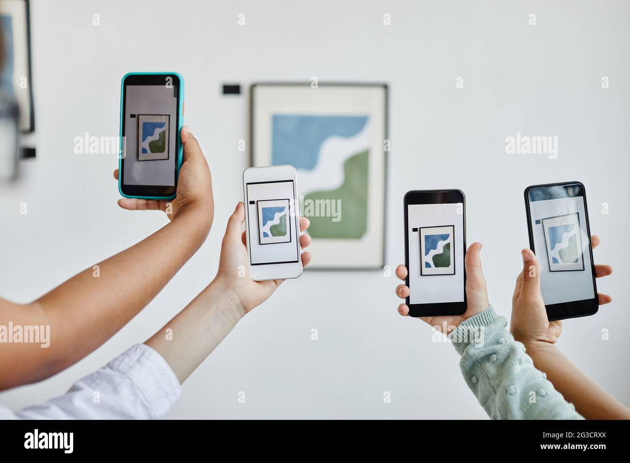 Background image of hands holding smartphones in modern art gallery and taking photos of paintings, digital world, copy space Stock Photo