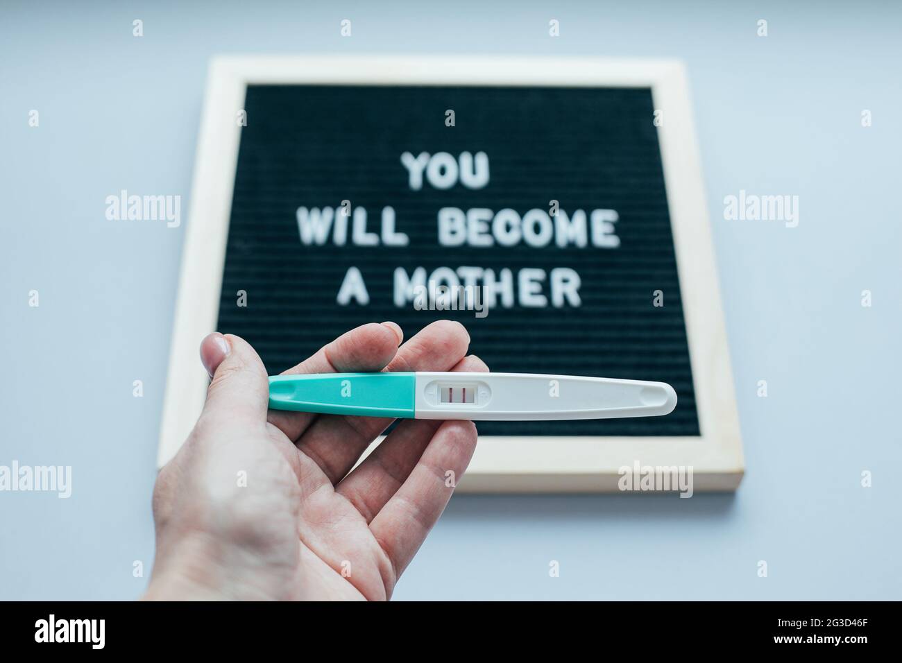 Pregnancy test with positive pregnan in woman's hand. Message board with text You will