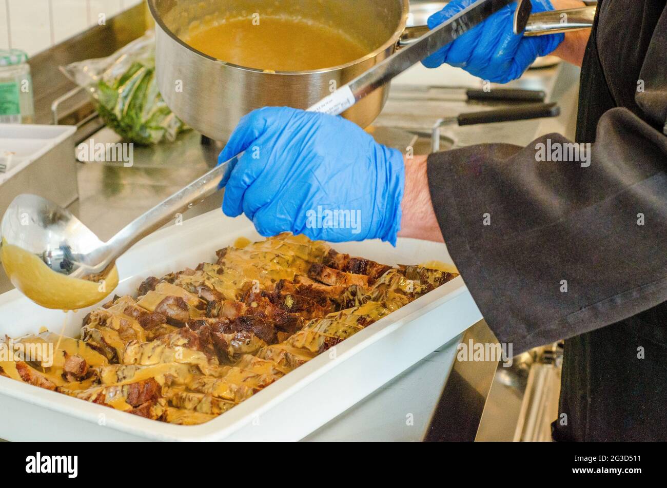 Chef is covering meat dish with sauce Stock Photo Alamy
