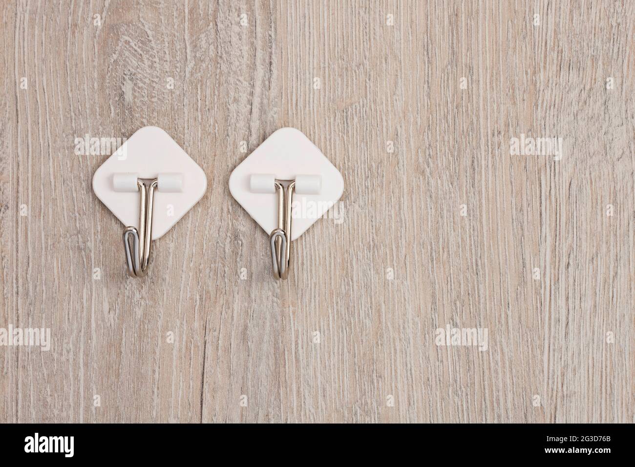 Two plastic adhesive utility wall fixed hooks with metal hooks for hanging clothes Stock Photo