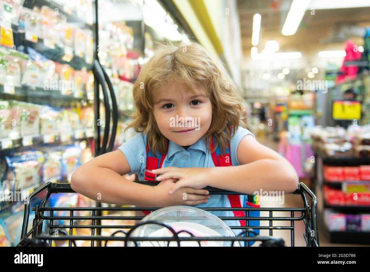 Kid with shopping basket purchasing food in a grocery store. Customers