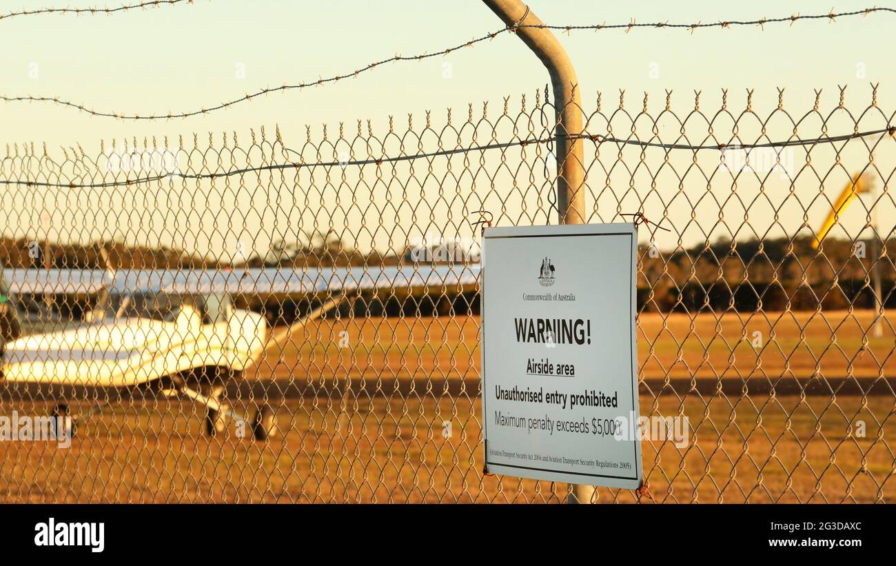 A close up of the Commonwelath of Australia warning sign at a regional airport or airfield. No unauthorised sign on a chicken wire security fence and Stock Photo