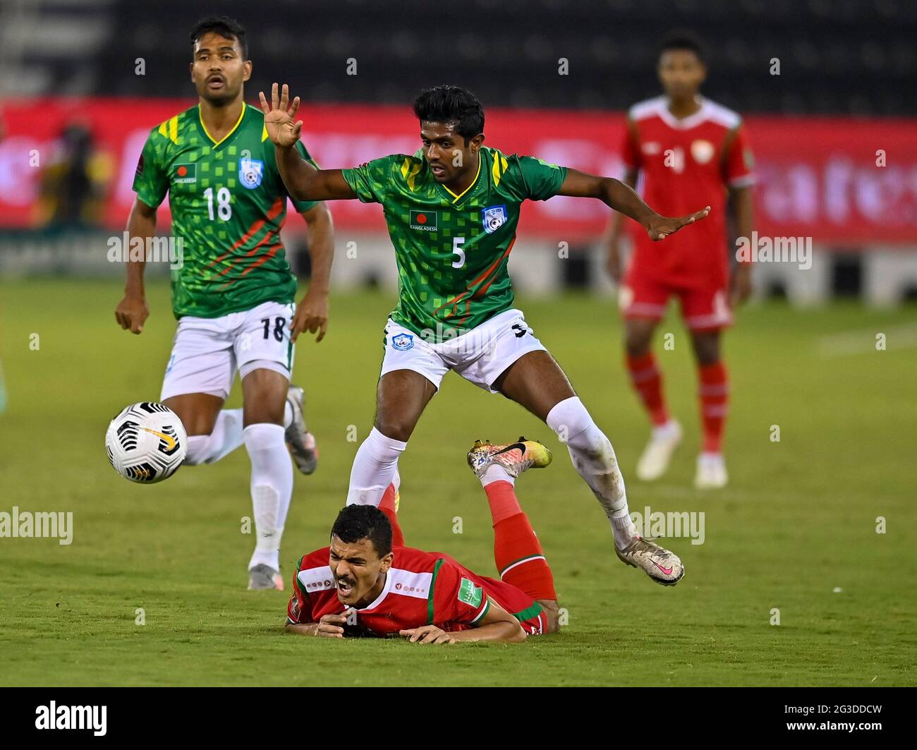 Doha, Qatar. 15th June, 2021. Mohammed Mubarak Al Ghafri (bottom) of Oman vies with Md Rimon Hossain (front R) of Bangladesh during the Group E football match at FIFA World Cup Qatar 2022 and AFC Asian Cup China 2023 Preliminary Joint Qualification in Doha, Qatar, June 15, 2021. Credit: Nikku/Xinhua/Alamy Live News Stock Photo