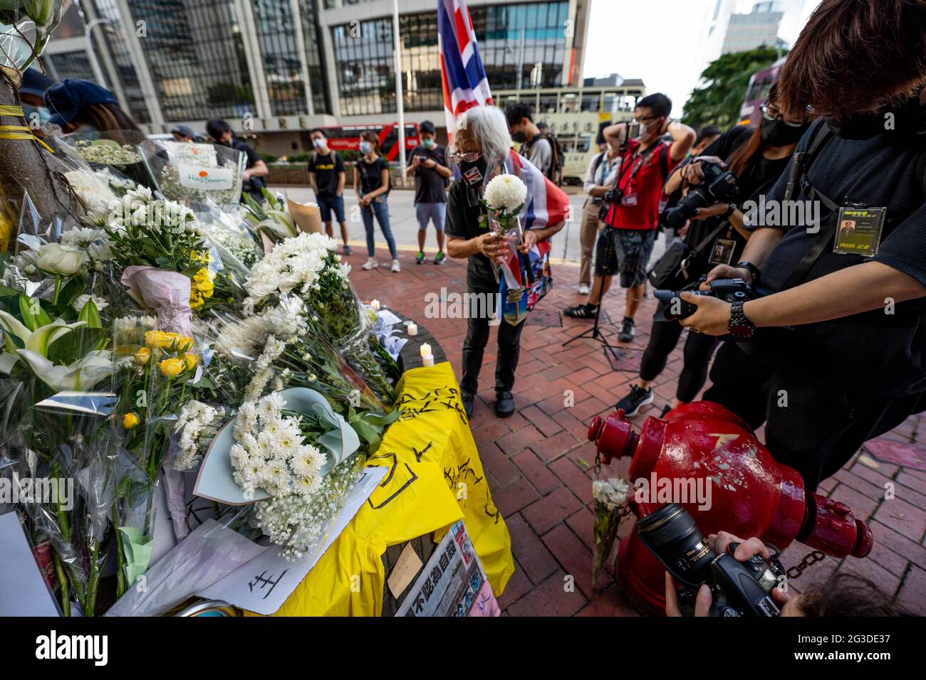 Hong Kong, China. 15th June, 2021. Grandma Wong, a well-known activist, lays flowers around a tree made as a makeshift shrine.Dozens of people laid white flowers, ribbons and lit candles to commemorate the two-year death of Marco Leung Ling-kit in Admiralty, Hong Kong. He was a man who fell to his death in a yellow raincoat from scaffolding of a nearby building during a social unrest, and had become an icon for the 2019-2020 Hong Kong protests. Credit: SOPA Images Limited/Alamy Live News Stock Photo