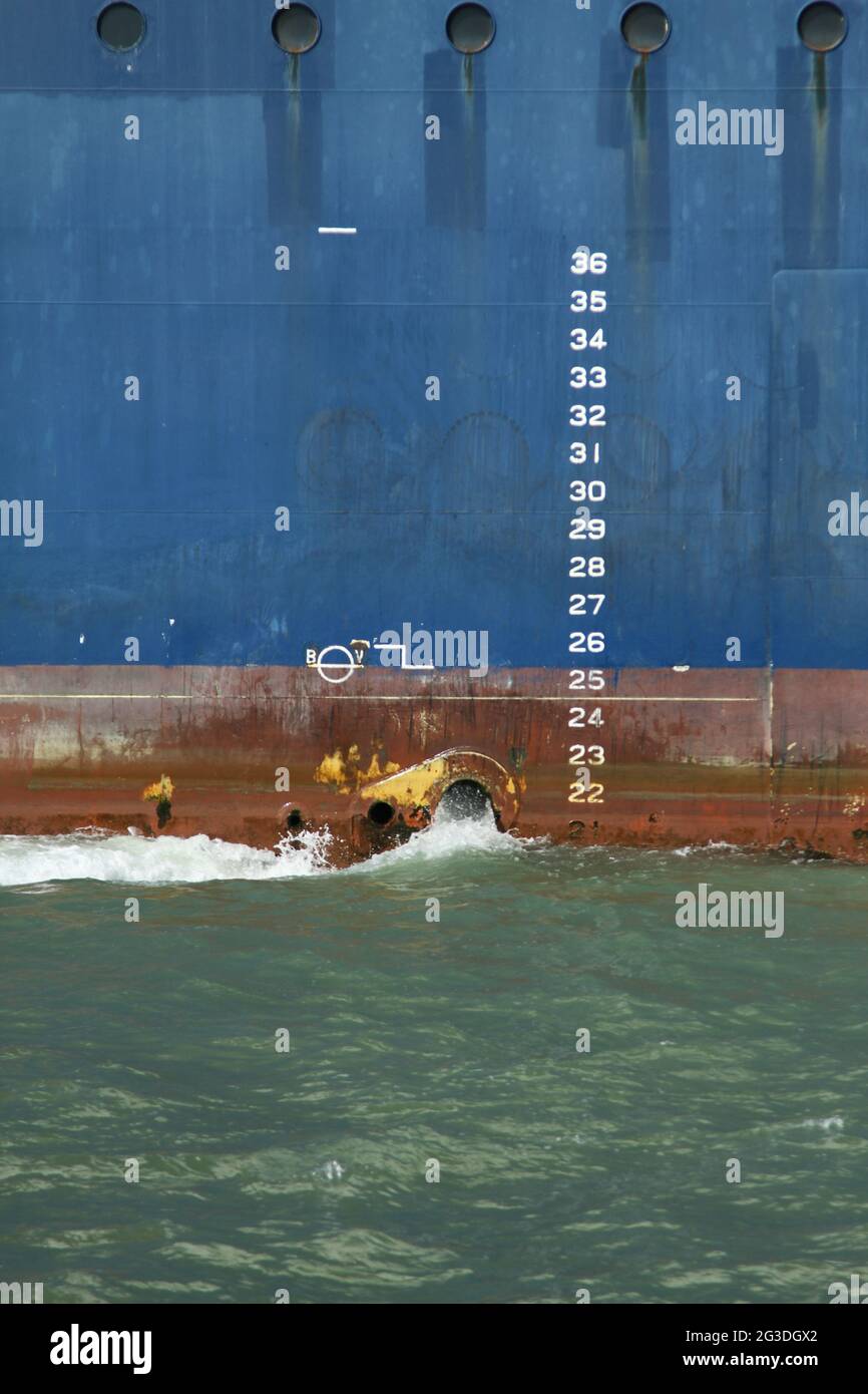 Cargo ship vessel showing ballast water being released as the ship enters shallow coastal waters
