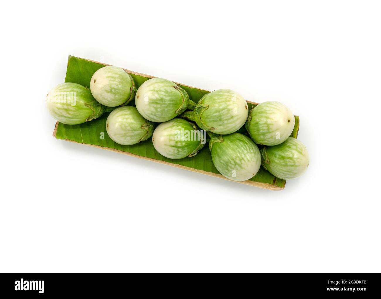 Fresh organic Thai eggplants on a banana leaf with a tray that made from a banana tree, the image on white background, top view Thai eggplant. Stock Photo