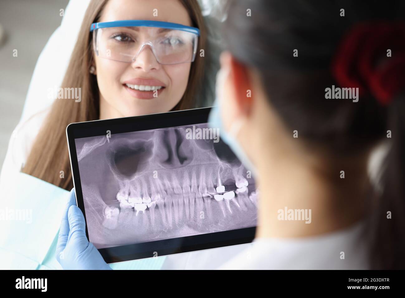 Dentist doctor examines X-ray picture on tablet screen in chair is ...