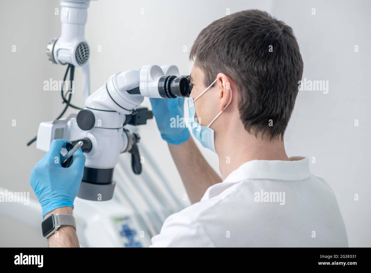 Male dentist working using optical medical instrument while doing a