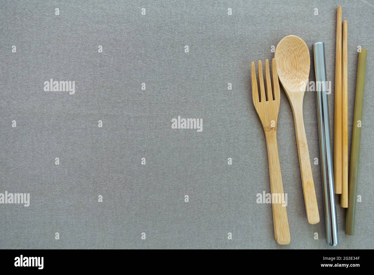 Reusable and environmentally friendly utensils, bamboo spoon, fork, chopsticks, small and big stainless steel straw on a beige copy space background. Stock Photo