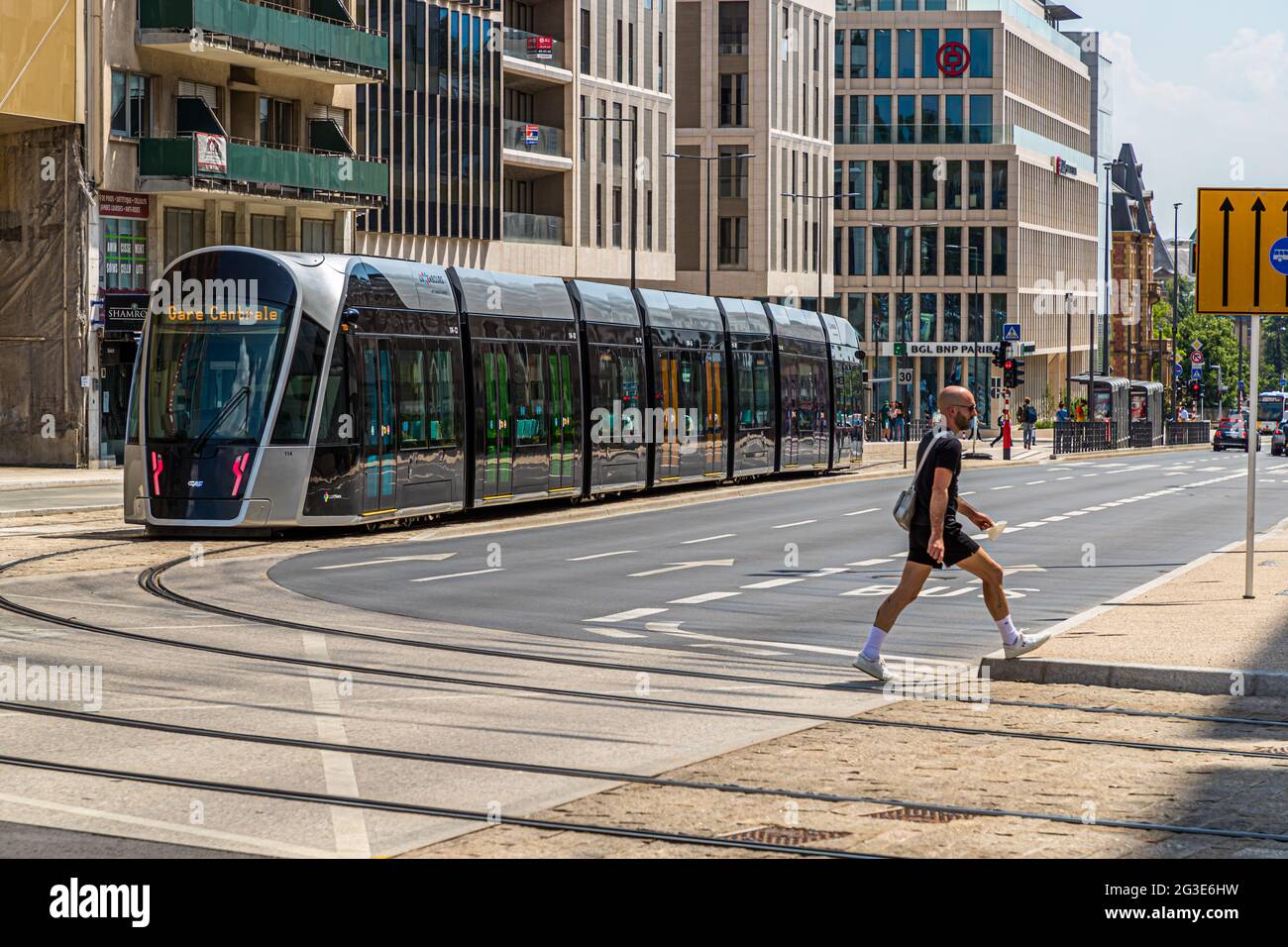 A pedestrian crosses the street in front of a streetcar in Luxembourg city Stock Photo