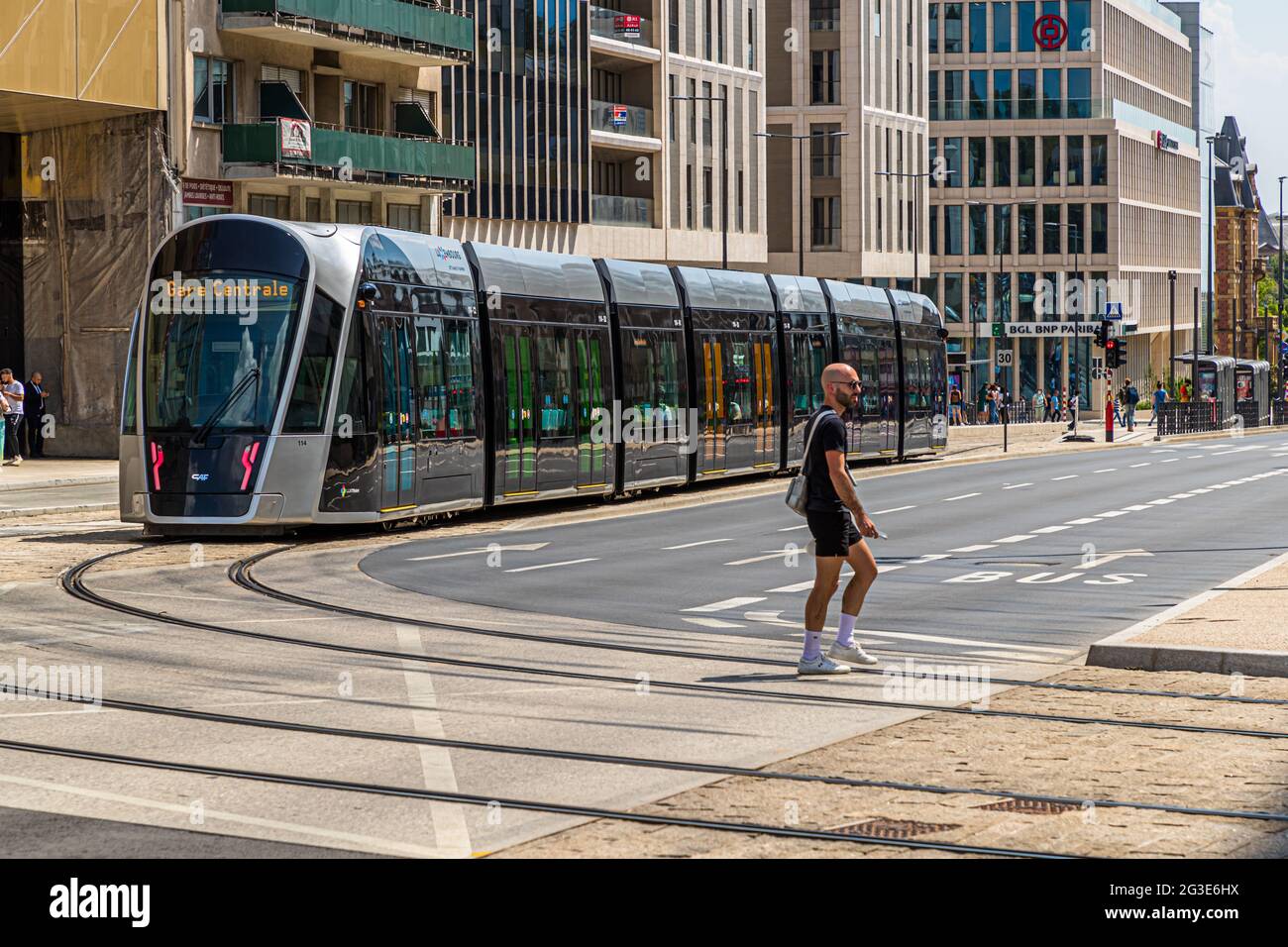 A pedestrian crosses the street in front of a streetcar in Luxembourg city. As in all of Luxembourg, the use of streetcars and trains are free of charge since the end of 2019 Stock Photo