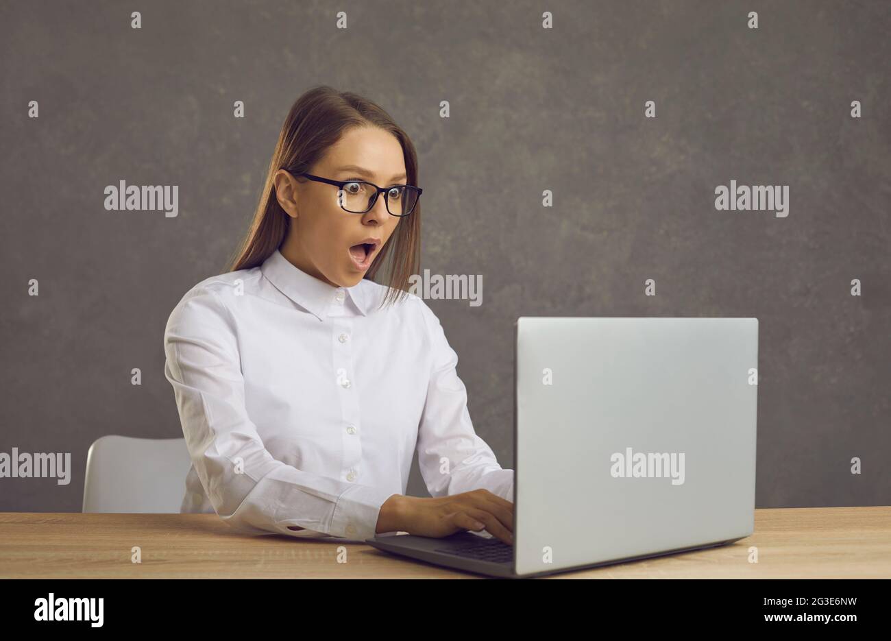 Portrait of young shocked astonished businesswoman woman working on laptop Stock Photo