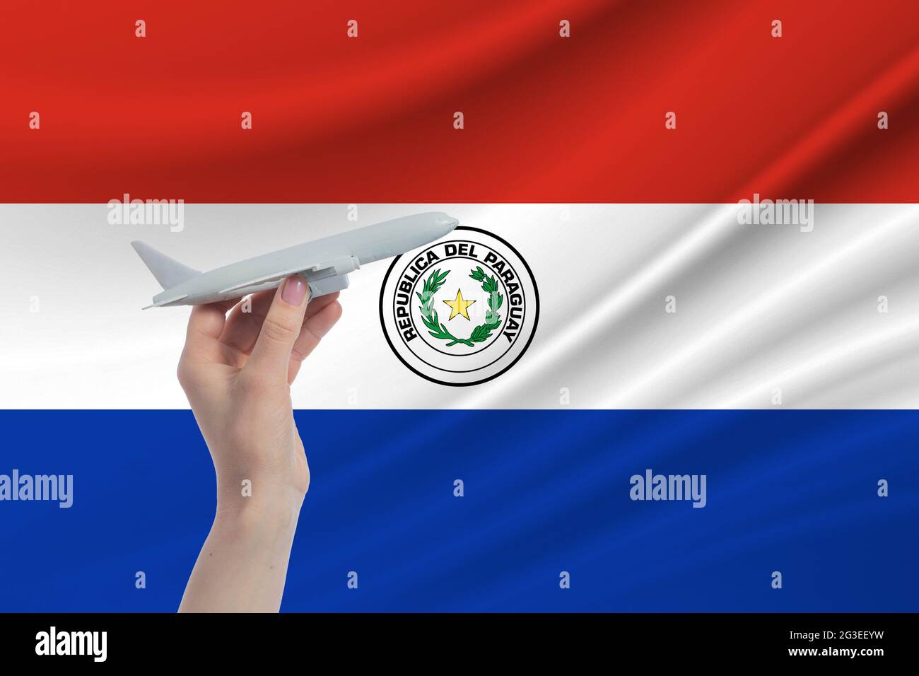 Airplane in hand with national flag of Paraguay. Travel to Paraguay. Stock Photo