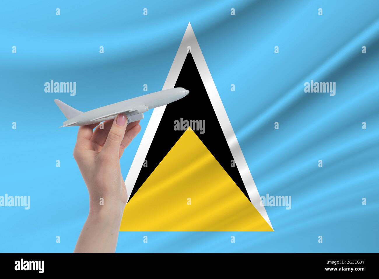 Airplane in hand with national flag of Saint Lucia. Travel to Saint Lucia. Stock Photo