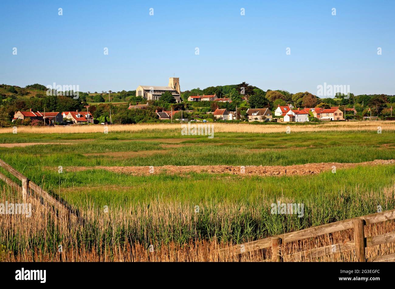 A view across Salthouse Marshes to the coastal village and Church in North Norfolk at Salthouse, Norfolk, England, United Kingdom. Stock Photo