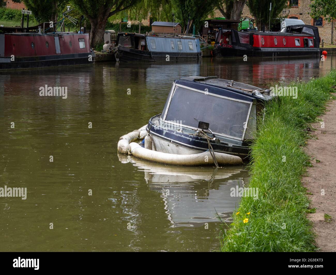 Semi derelict cabin cruiser kept afloat with a buoyancy aid, Grand Union canal, Cosgrove, Northamptonshire, UK Stock Photo