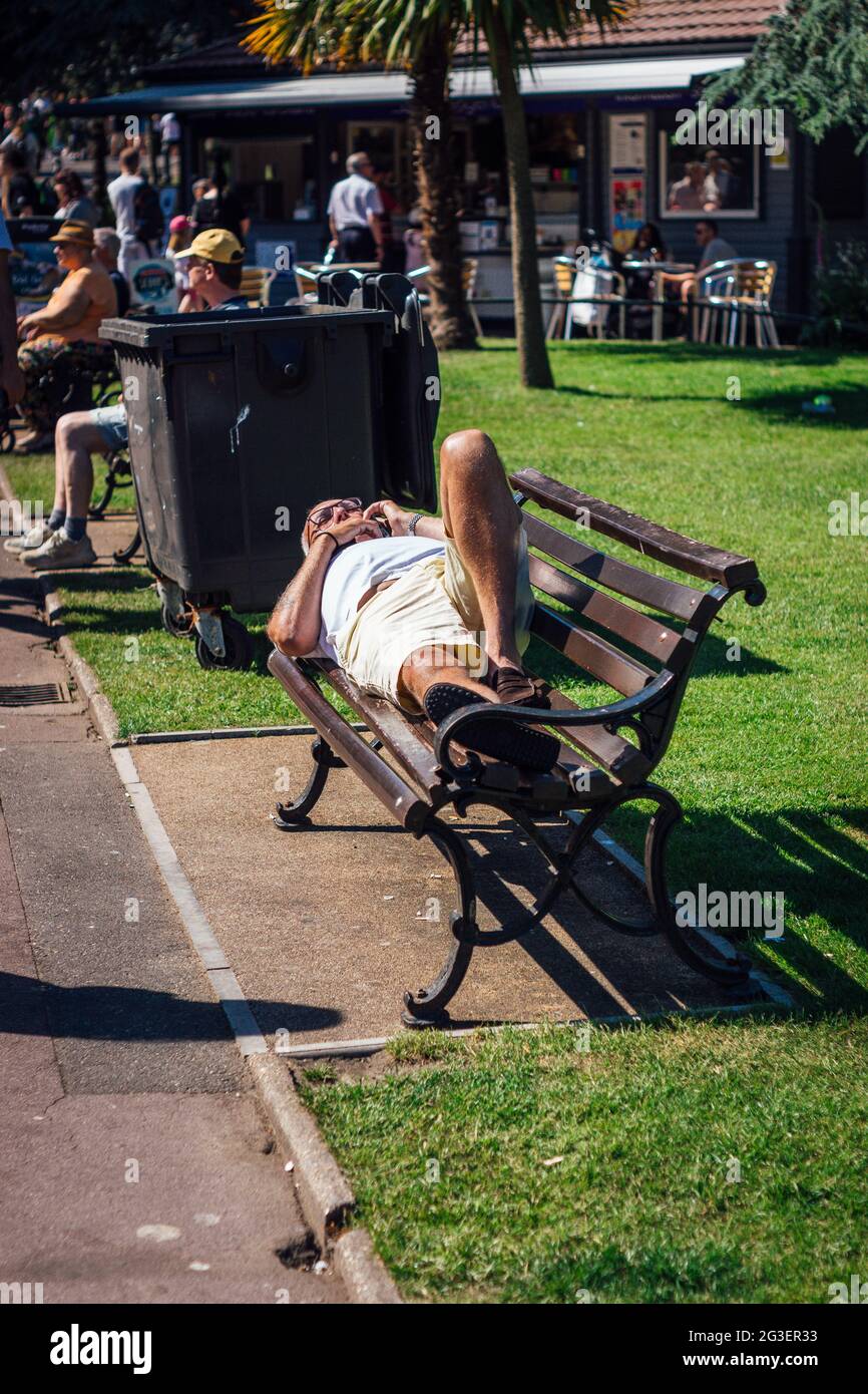 Older man sunbathing on a bench in Bournemouth Gardens, Bournemouth UK. Stock Photo