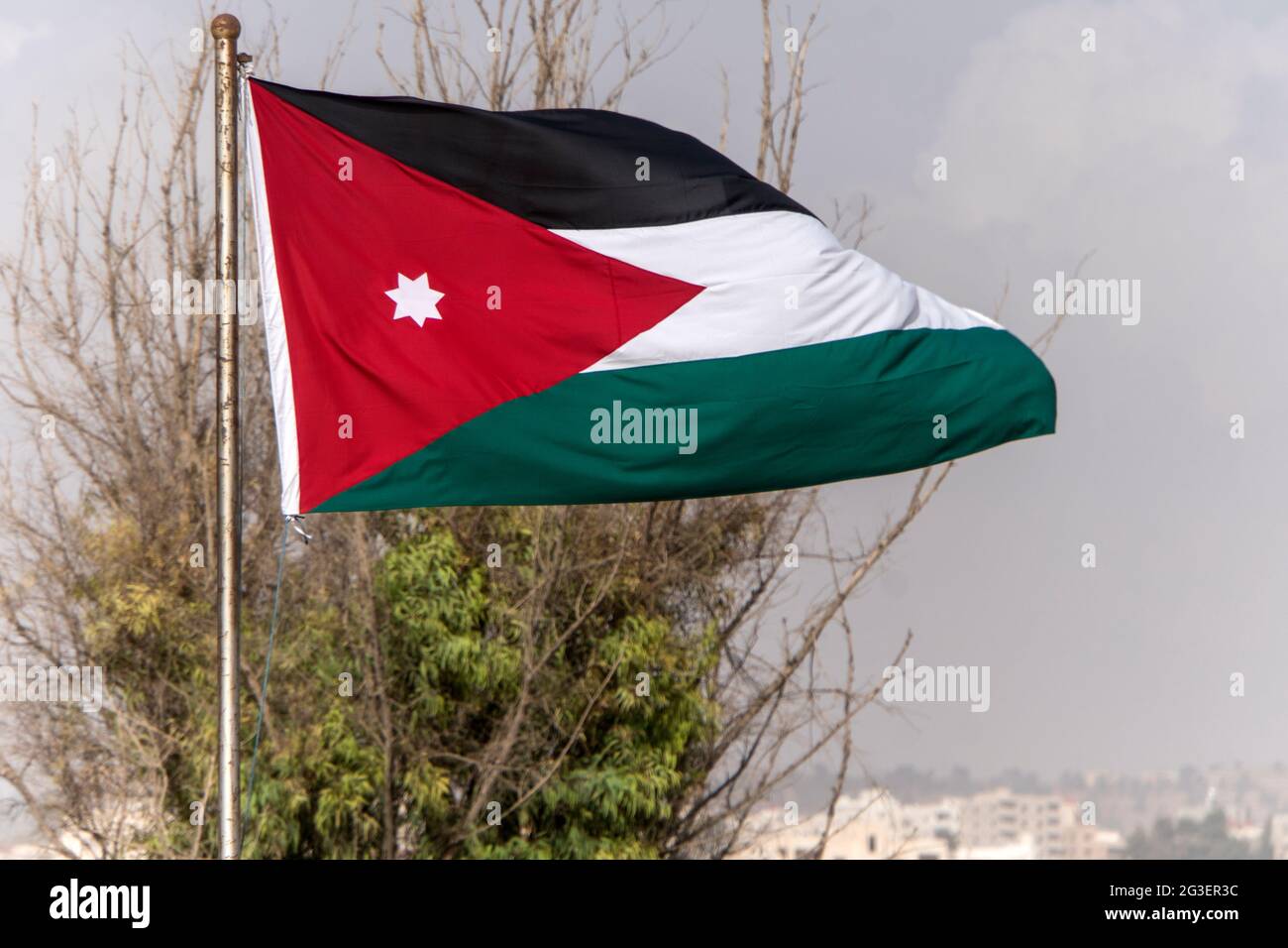 tricolor flag of Jordan on the background of the old poor of the city and blue sky Stock Photo