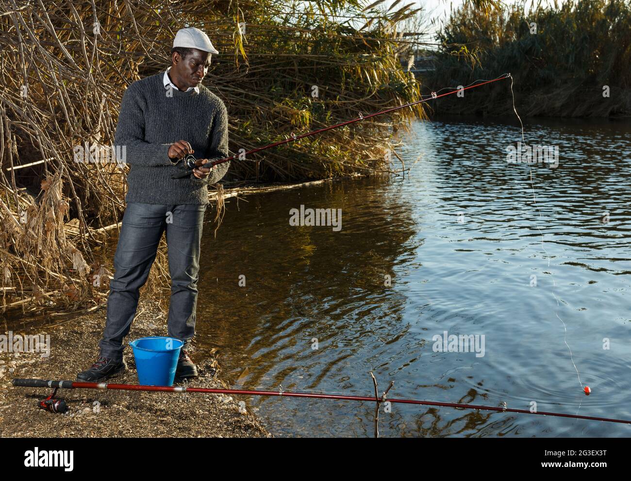 Afro fisherman standing near river Stock Photo