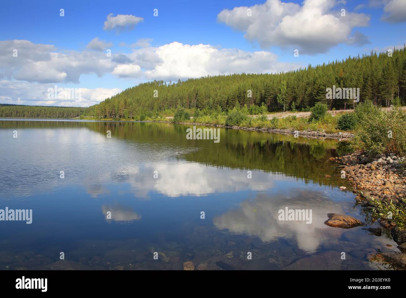 Beautiful landscape with a lake which has reflections of the trees and clouds. The lake lies within the Arctic circle near Polcirkeln, Northern Sweden. Stock Photo