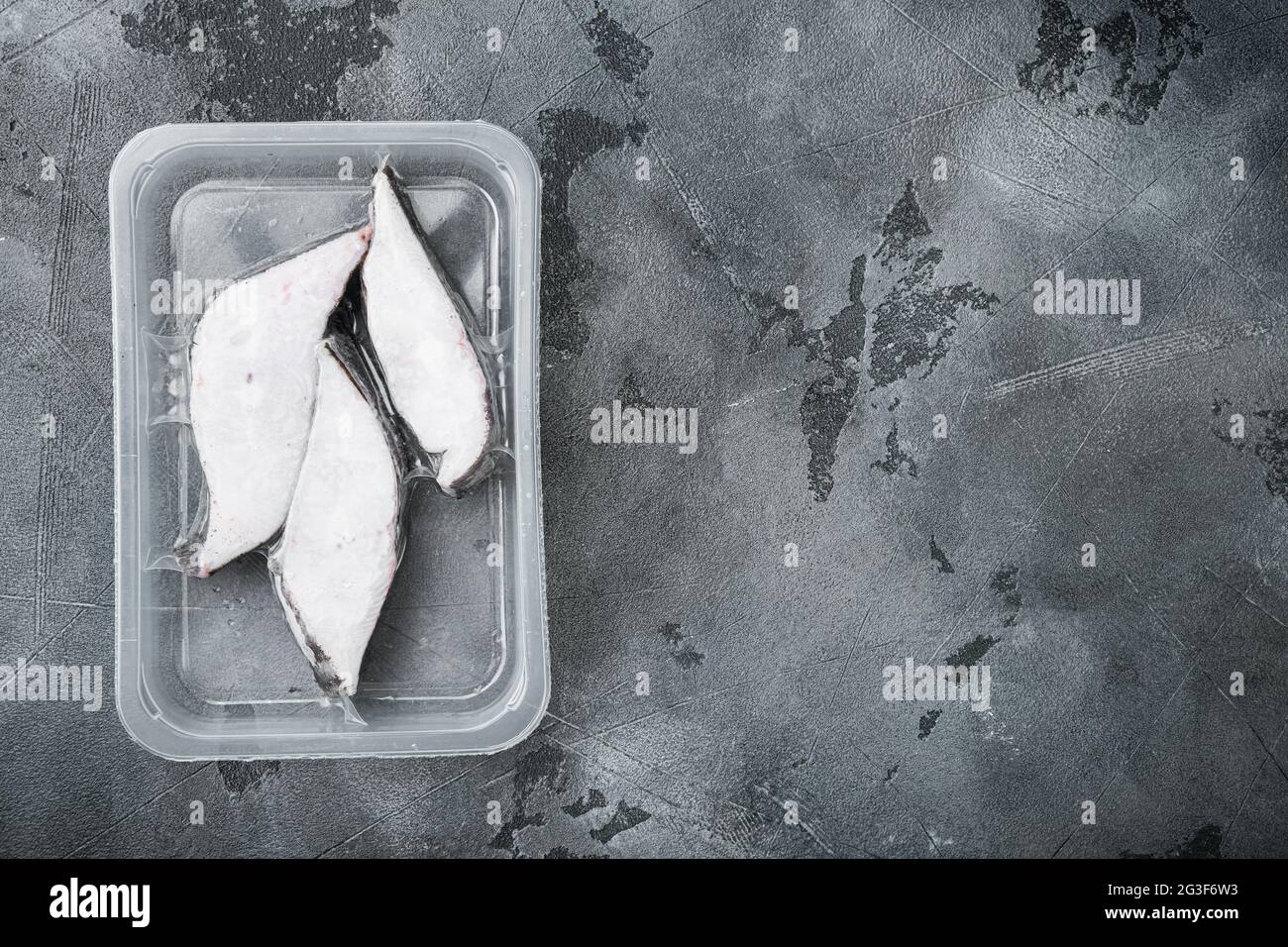Raw fillets frozen halibut airtight vacuum pack set, on gray stone table background, top view