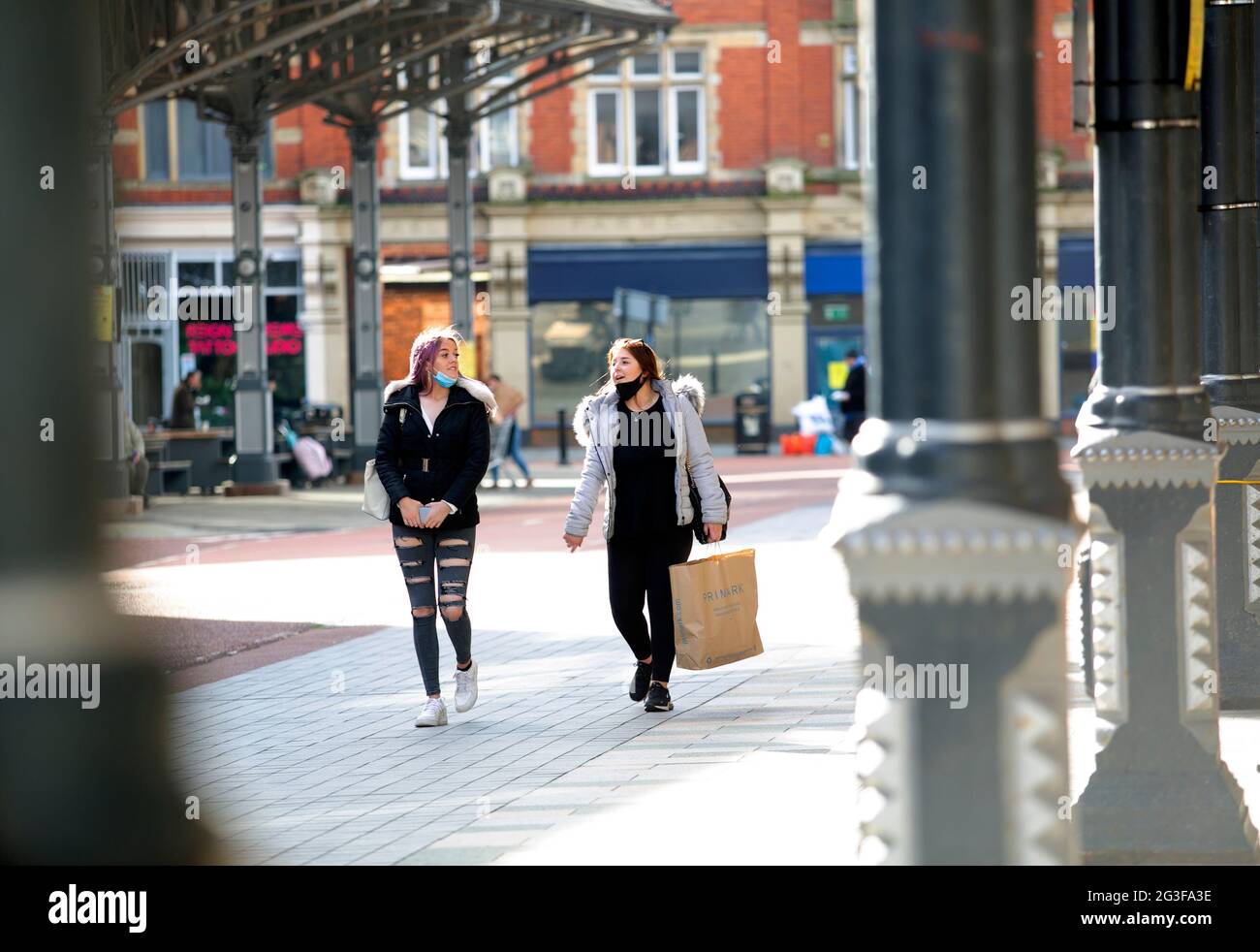 Two young women in face masks with shopping bags walk through the city ...