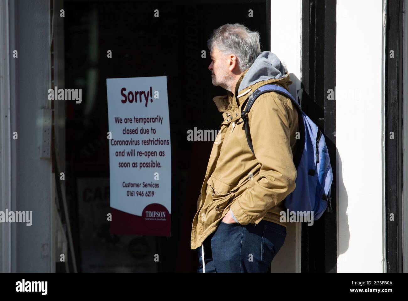 A man stands outside a closed shop in Harrogate in north Yorkshire as the coronavirus epidemic closes shops on the high street. Stock Photo