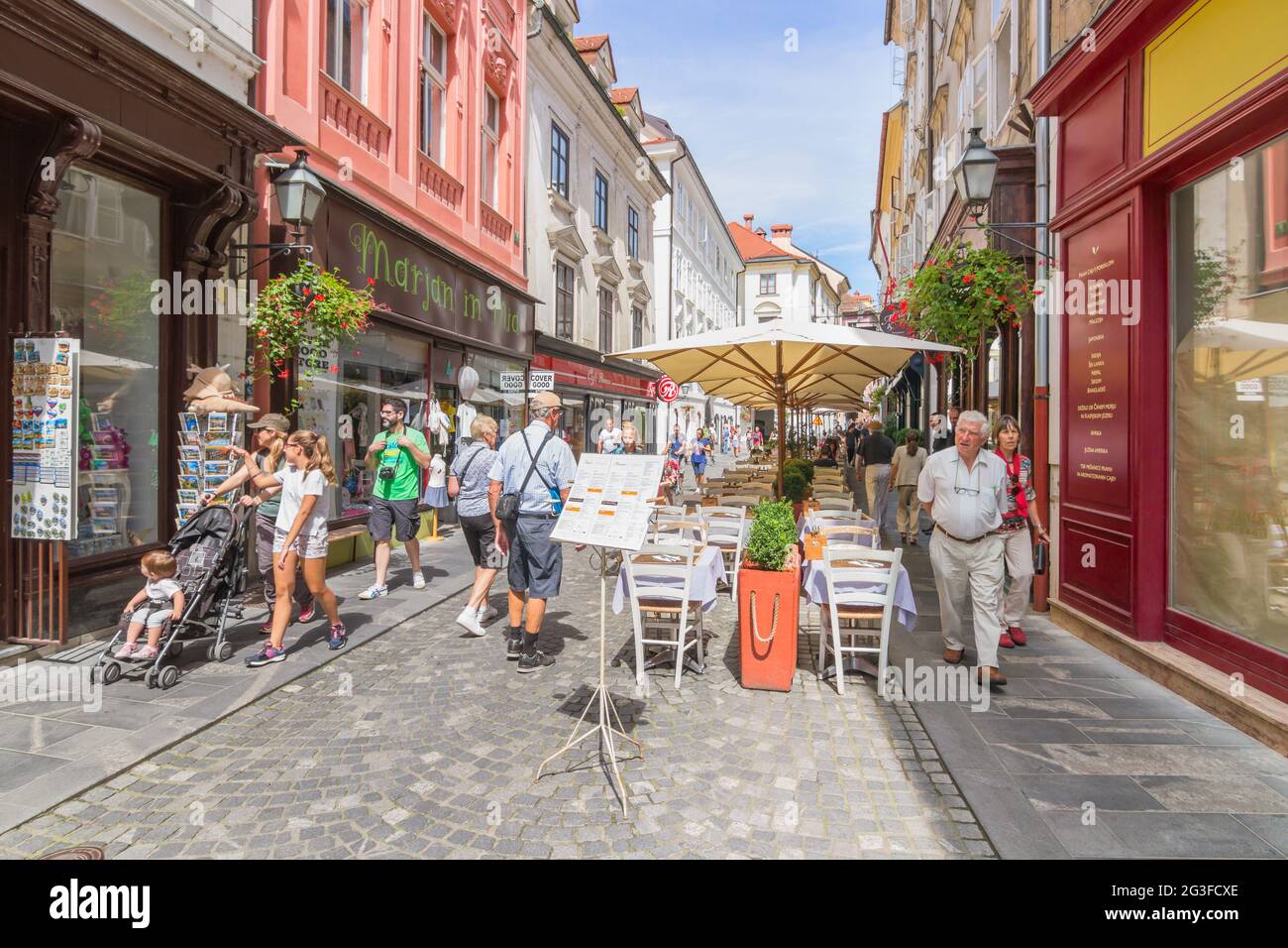 Ljubljana, Slovenia - August 15, 2018: Tourists walking through the picturesque Stari street in a sunny day in the old center, along restaurant tables Stock Photo