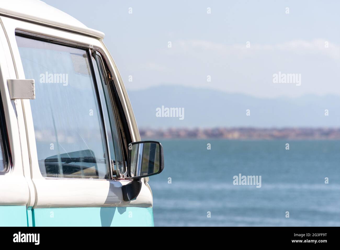 Close up of turquoise Volkswagen van parked near the beach, summer vacation concept. Stock Photo
