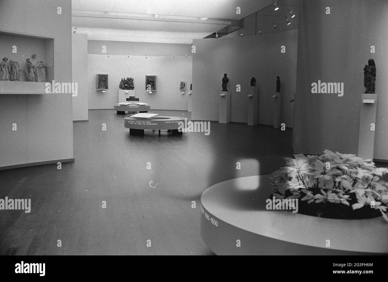 Room with images on pedestals and benches with information panels and flower decoration; Exhibition Adriaen van Wesel. . Stock Photo