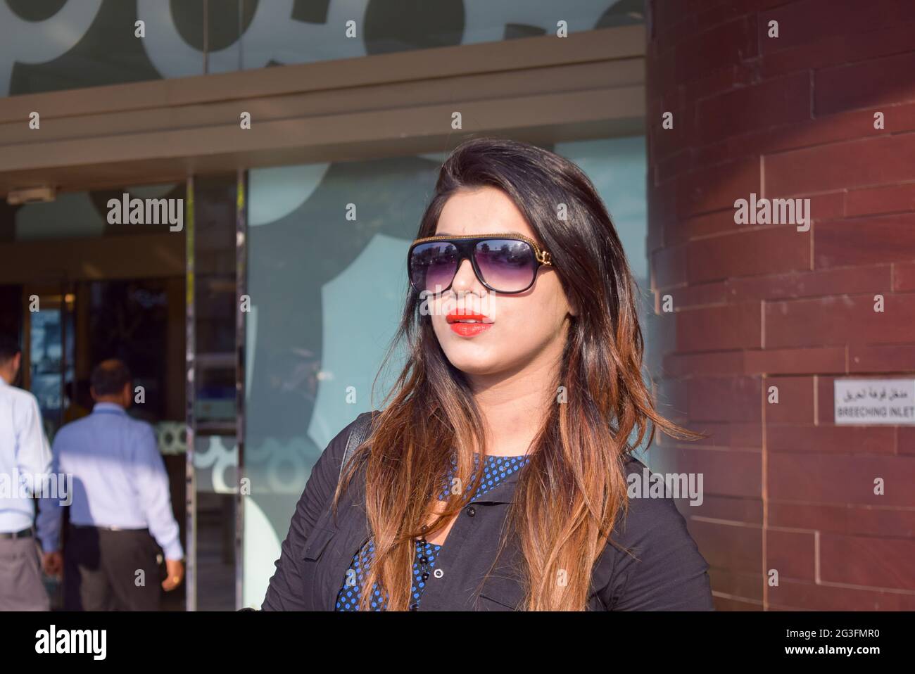 A pretty Asian woman wearing sunglasses with a smile standing outside in the street, fashion concept. Stock Photo