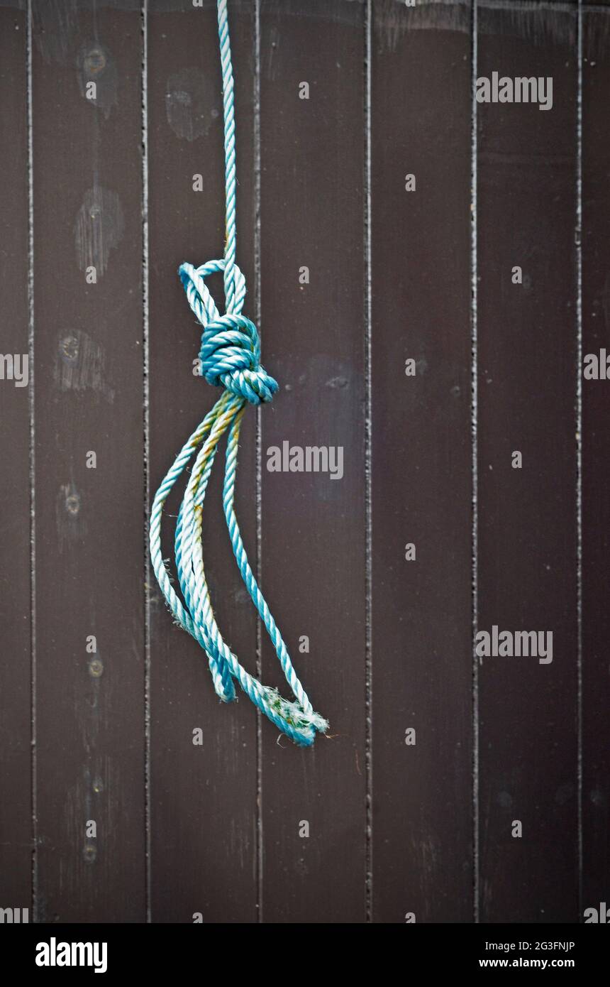 hanging synthetic fibre blue rope loop on dark painted wooden door Stock Photo