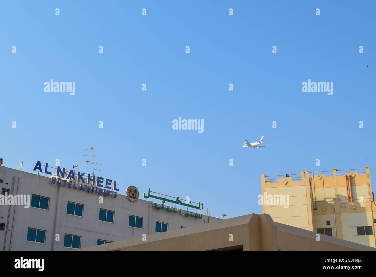 Emirates airline plane over Deira area in the Dubai City. Stock Photo