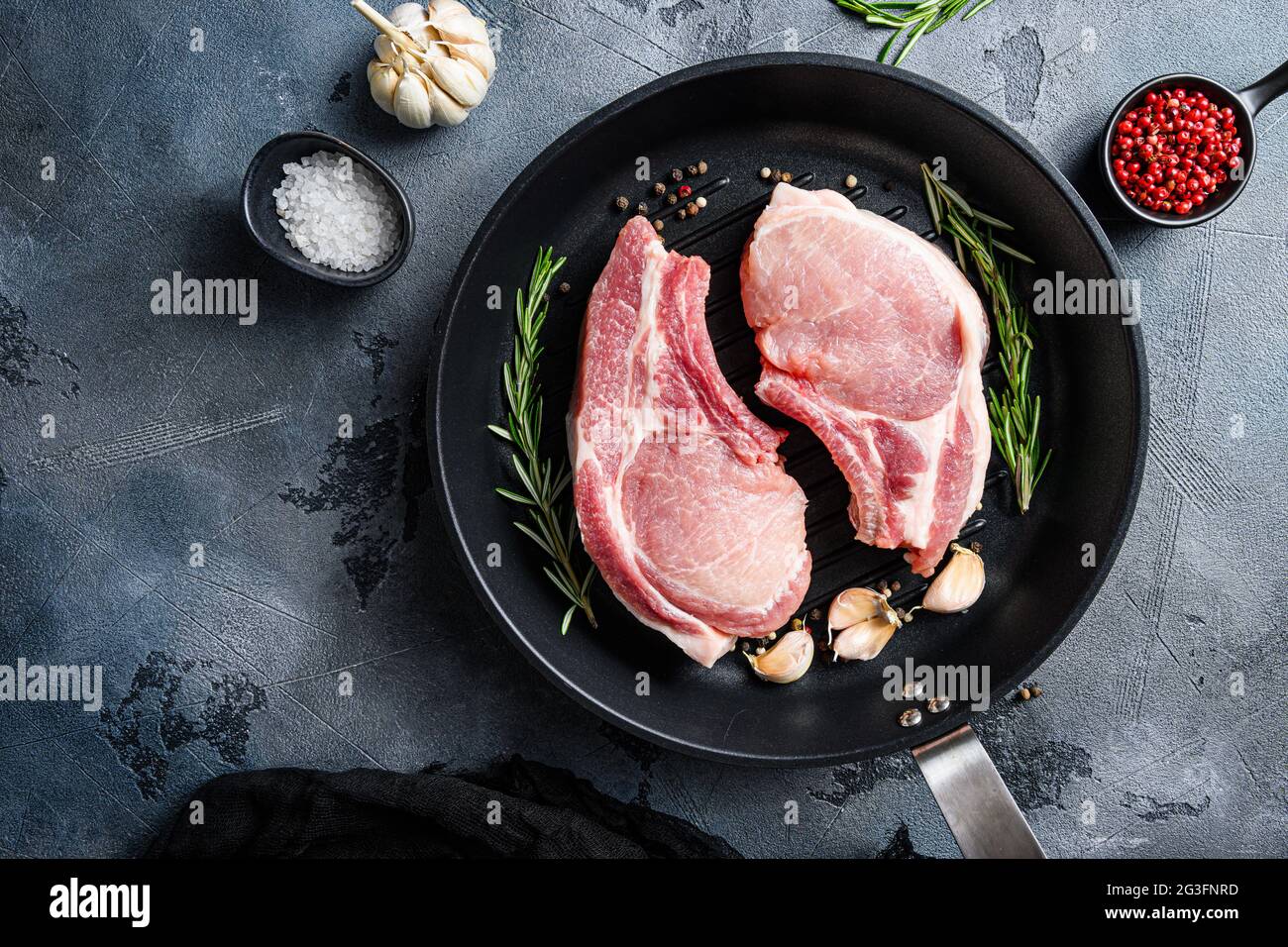 Pork steaks, fillets for grilling, baking in frying pan black skillet with herbs, spices top view flatlay . Stock Photo