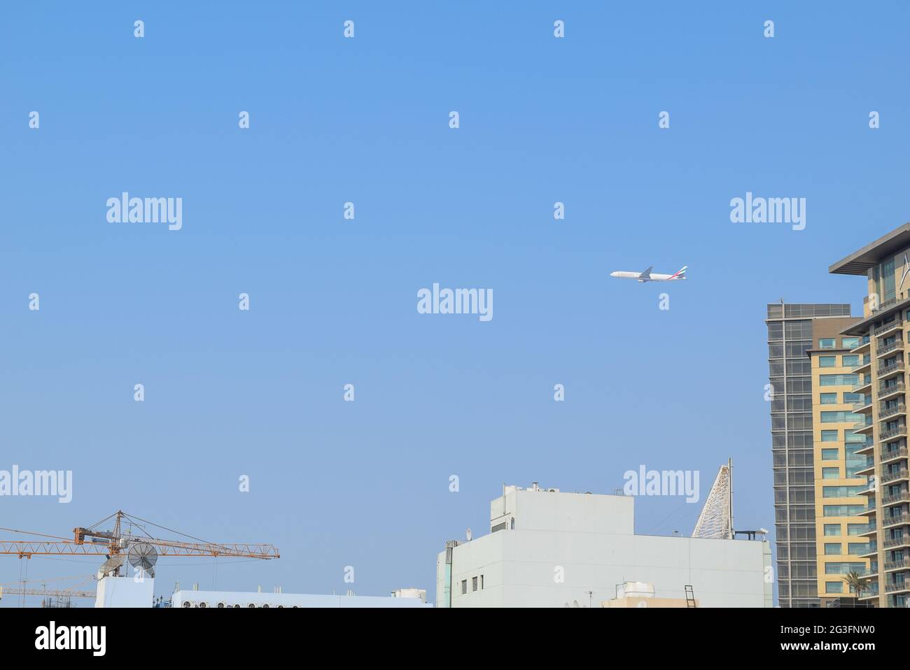 Emirates airline plane over Deira area in the Dubai City. Stock Photo