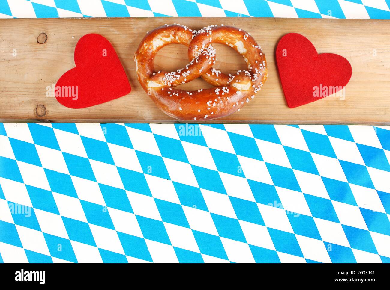 Wooden board with pretzel and hearts on diamond pattern - bavarian pretzel,Salty pretzels on chequered bavarian background Stock Photo