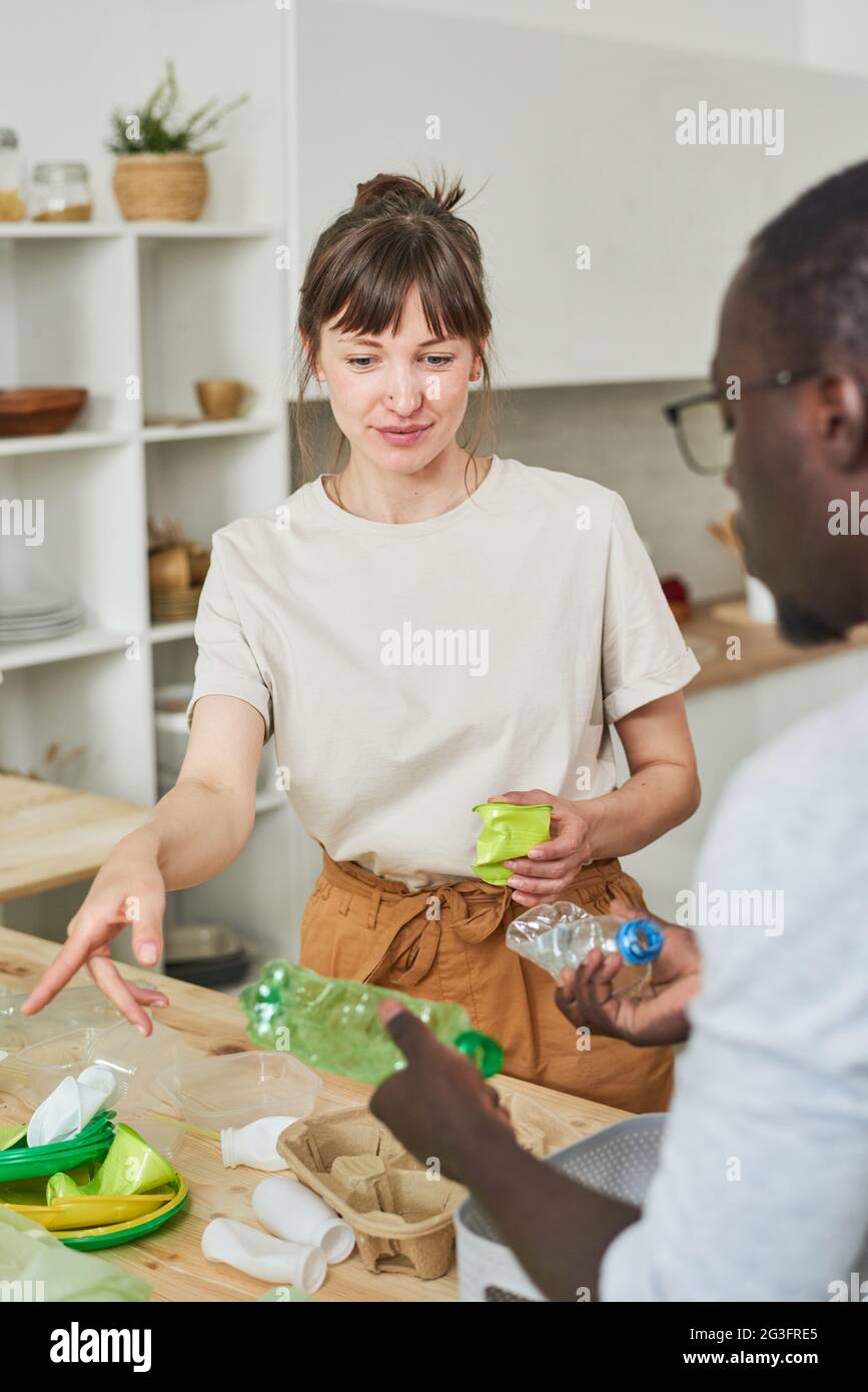 Young couple sorting the garbage in packets together standing in the kitchen Stock Photo