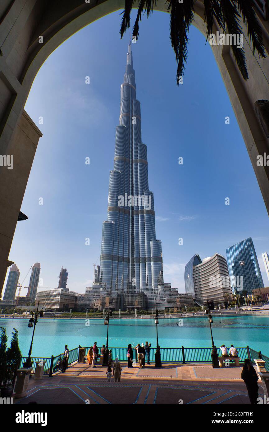 Looking up at the world's tallest building, the Burj Khalifa in Dubai, the UAE. Tall archway framing and people viewing with blue sky background. Stock Photo