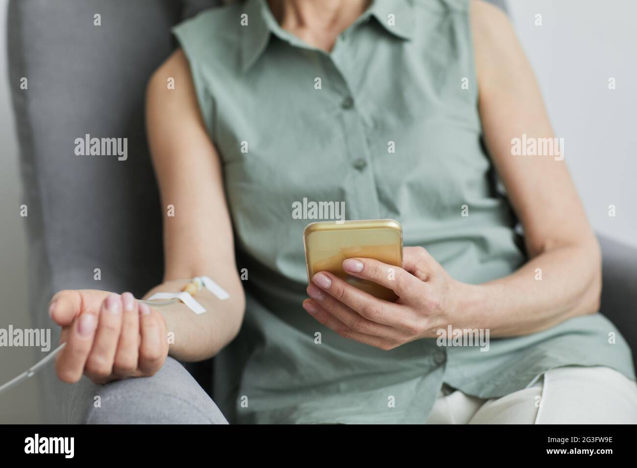 Minimal close up of unrecognizable woman getting IV drip and using smartphone, copy space Stock Photo