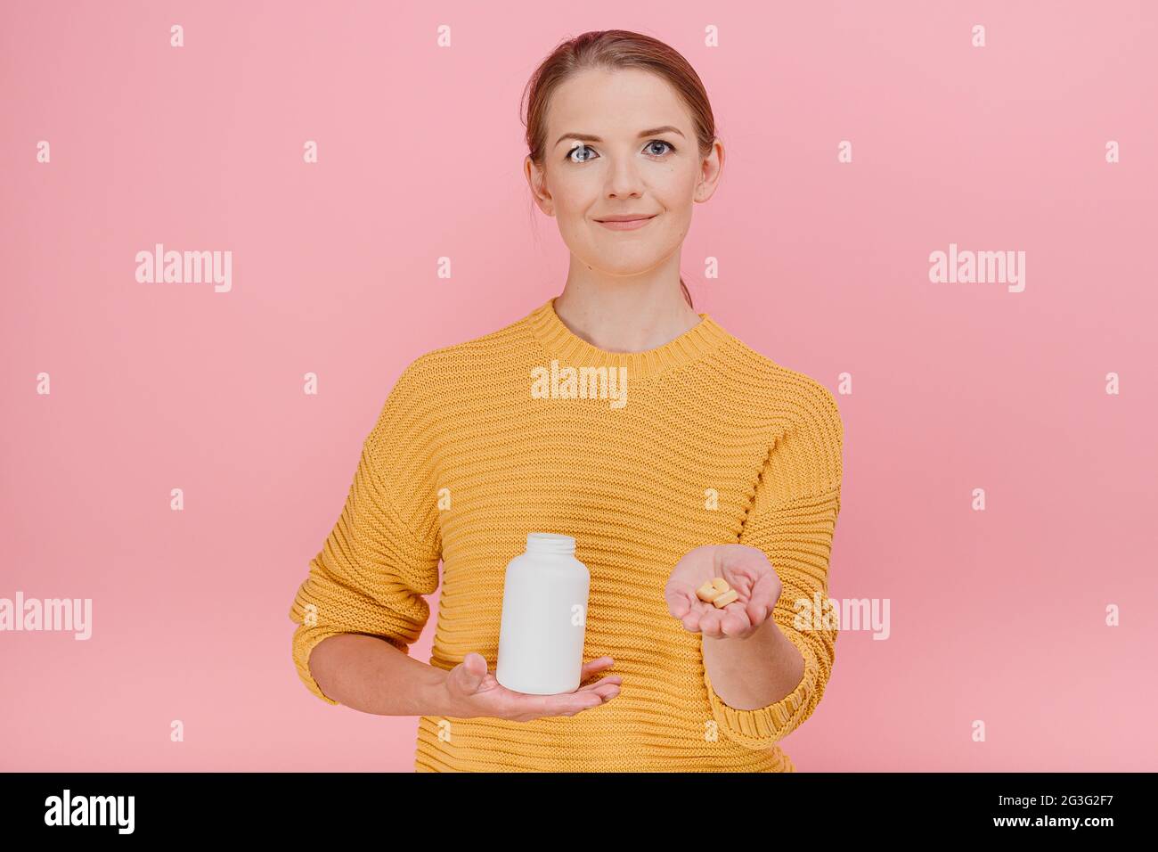 Attractive housewife woman holds tube with vitamins in hand and give pills to someone set looks at the camera treatment and prevention of diseases med Stock Photo