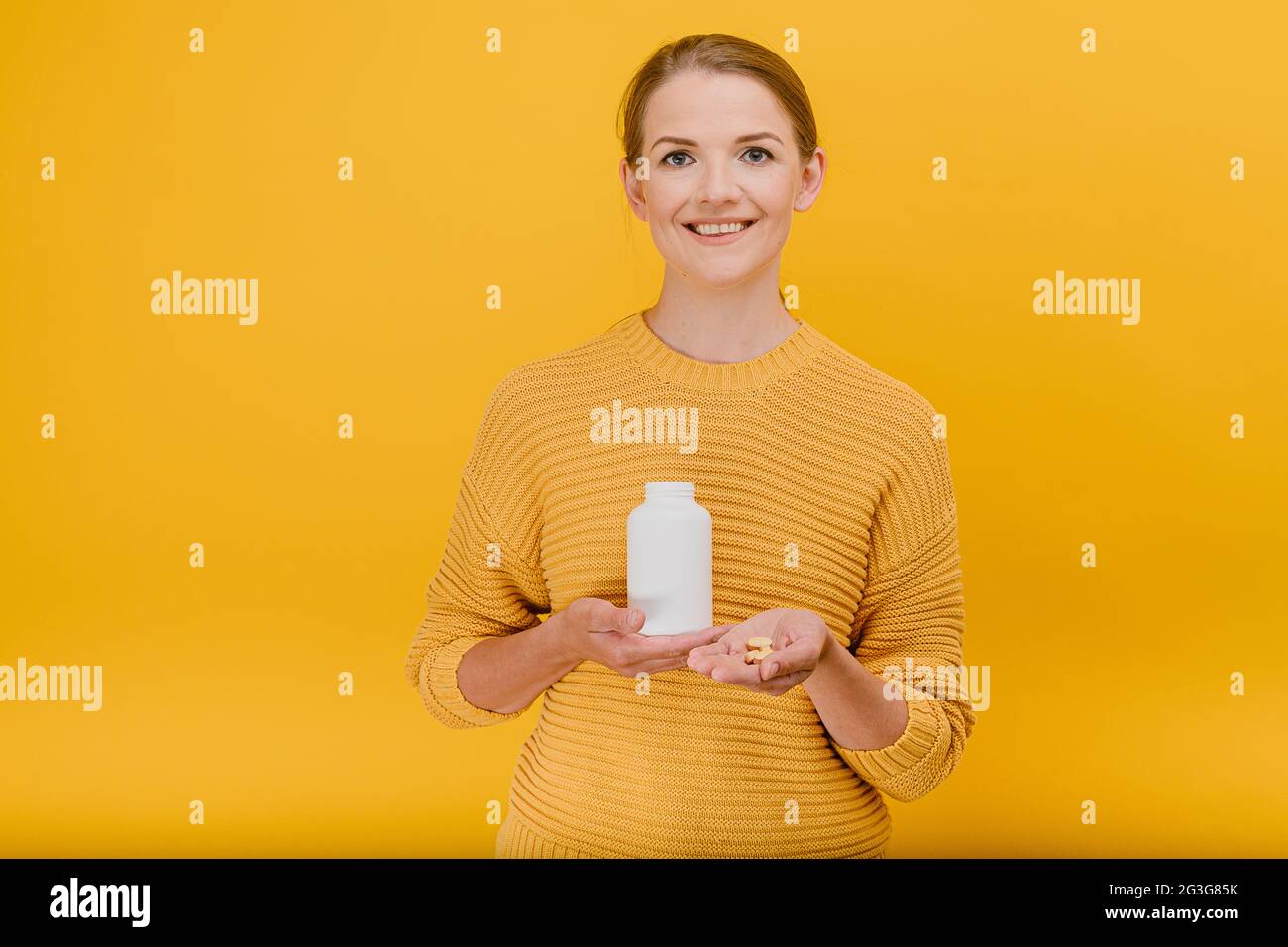 Attractive housewife woman holds tube with vitamins in hand and give pills to someone set, smiling having good mood looks at the camera treatment and Stock Photo