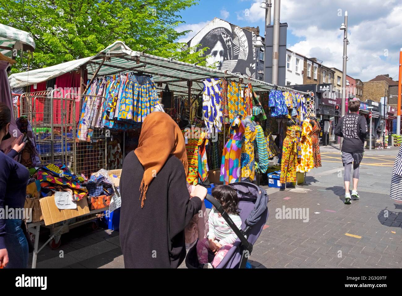 African textiles and clothing for sale on traders market stall people shopping shoppers in Walthamstow High Street London E17 England UK  KATHY DEWITT Stock Photo