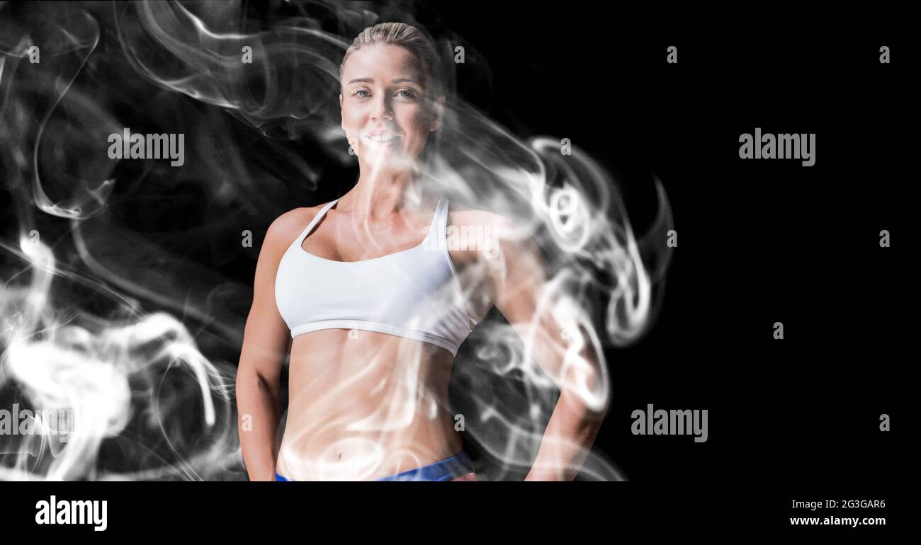Portrait of caucasian female athlete smiling against smoke effect on